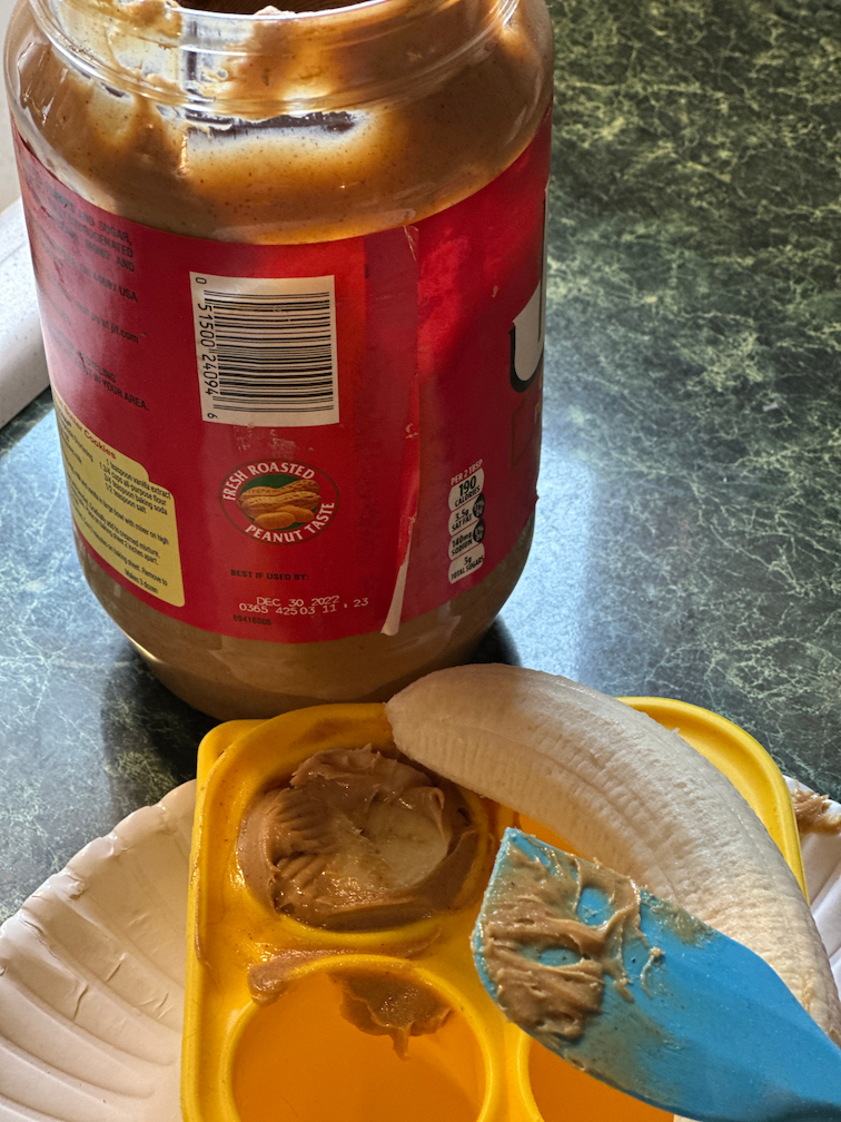 jar of peanut butter with a banana and a pupsicle treat tray